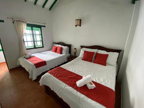 um quarto com 2 camas com lençóis vermelhos e brancos em Posada La Rioja em Villa de Leyva