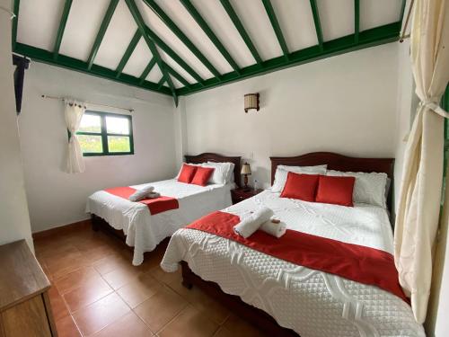 um quarto com 2 camas com lençóis vermelhos e brancos em Posada La Rioja em Villa de Leyva