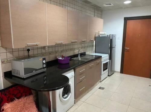 a kitchen with a sink and a stove and a refrigerator at Awesome studio at silicon oasis in Dubai