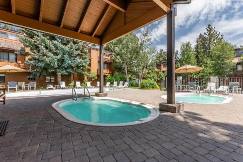 a patio with two swimming pools with tables and umbrellas at Snowflower #47 - Updated 2 Bedroom & Loft, 3 Bath, Sleeps 8, Steps away from Free Town Shuttle in Mammoth Lakes
