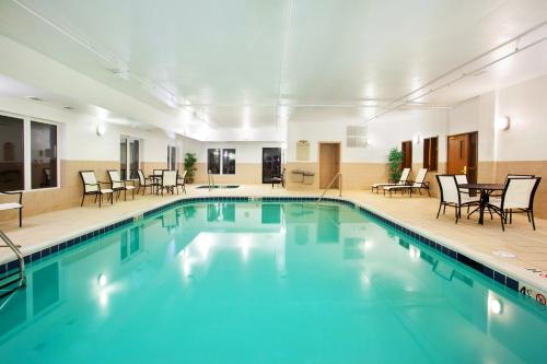een zwembad in een hotel met stoelen en tafels bij Holiday Inn Express Hotel & Suites Mattoon, an IHG Hotel in Mattoon