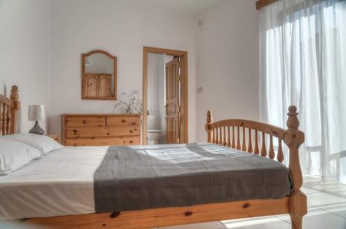 um quarto com uma cama de madeira e uma grande janela em Double bedroom with ensuite in spacious corner apartment em Birkirkara