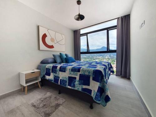 ein Schlafzimmer mit einem Bett und einem großen Fenster in der Unterkunft Sky Flat Panoramic View 2Brm@Avitat Link w/Pool &Gym in Antiguo Cuscatlán