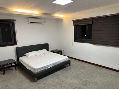 1 dormitorio con 1 cama en una habitación con 2 ventanas en S Pool Villa Clark 天天别墅酒店, en Ángeles