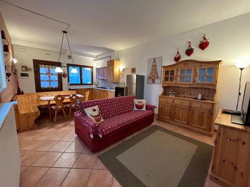 a living room with a red couch and a kitchen at La tana del lupo in Camporosso in Valcanale