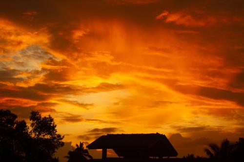 a sunset with a building in the foreground at Golden Town Hotel in Tangalle