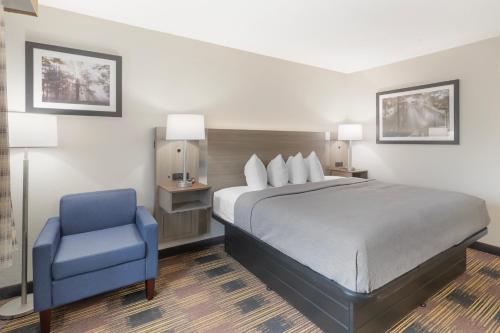 a bedroom with a bed and a blue chair at Quality Inn Newton at I-80 in Newton