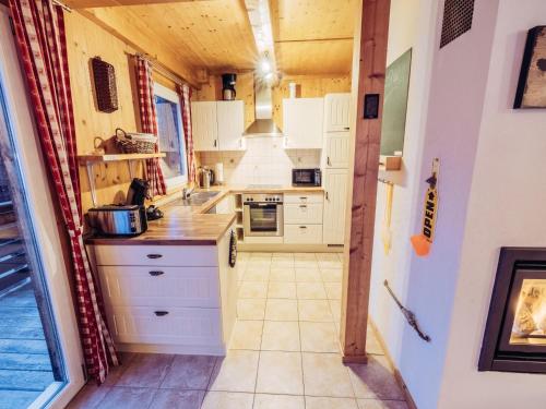 uma cozinha com armários brancos e piso em azulejo em Woody 13 em Sankt Lorenzen ob Murau