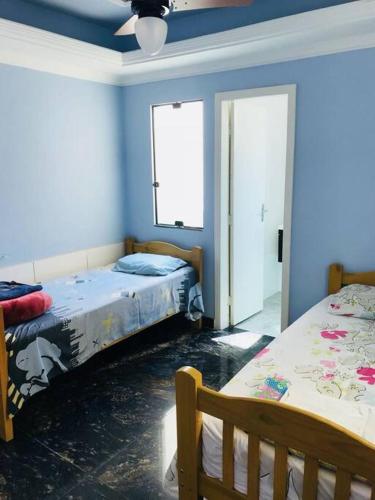 two beds in a room with blue walls at Casa confortável p/13/14/18 pessoas c 4/5/6 suítes in Belo Horizonte