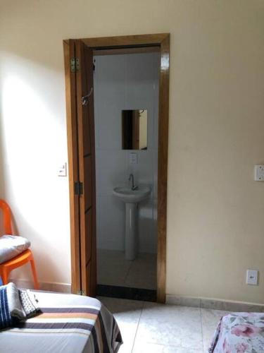 a bathroom with a sink and a door leading to a bedroom at Casa confortável p/13/14/18 pessoas c 4/5/6 suítes in Belo Horizonte