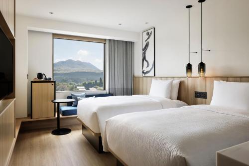 two beds in a hotel room with a view at Fairfield by Marriott Kumamoto Aso in Aso