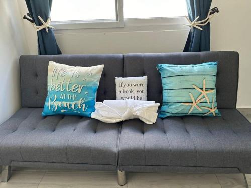 a gray couch with pillows on it with a window at Villa CAS. nueva en Palma Real in La Ceiba