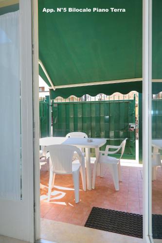 a white table and chairs and a green wall at 3V Apartments Bardolino in Bardolino