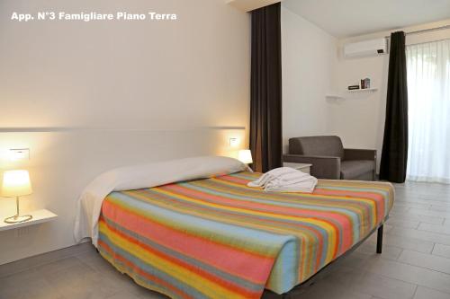 a bedroom with a bed with a colorful striped blanket at 3V Apartments Bardolino in Bardolino