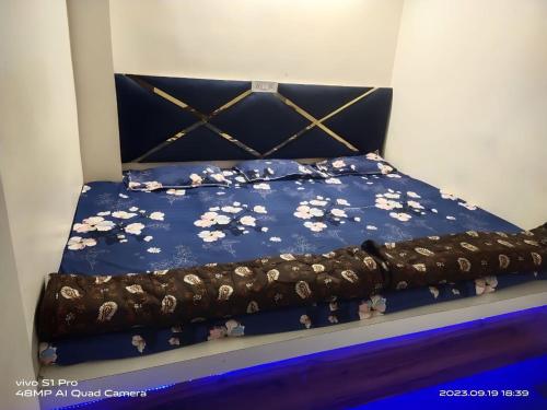 a bed with a blue bedspread with flowers on it at PRABHU PALACE in Ujjain