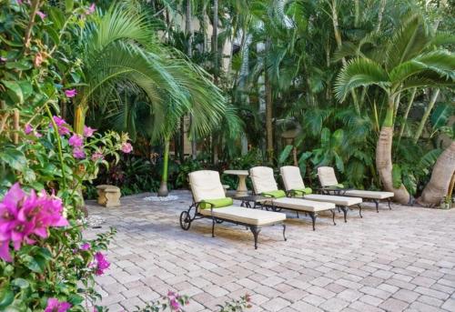 a row of lounge chairs sitting on a brick patio at Hemingway Suites at Palm Beach Hotel Island in Palm Beach
