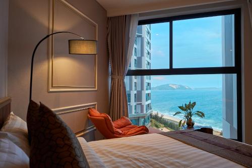 a hotel room with a bed and a window with the ocean at Apec Mandala Wyndham Mui Ne Ngoc Linh in Ấp Long Sơn