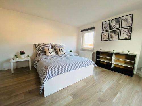 a white bedroom with a bed and a wooden floor at Ihr Zimmer in Freital bei Dresden in Freital