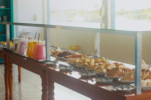 a buffet line with plates of food and drinks at Pousada Costa da Riviera PISCINA CLIMATIZADA in Bertioga