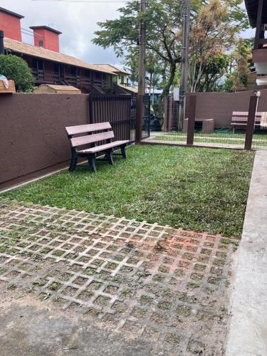 a park bench sitting on the grass near a building at Residencial Casa Laranja - Casas na Praia da Ferrugem in Garopaba
