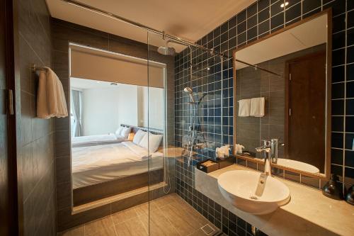 La salle de bains est pourvue d'un lavabo, d'un miroir et d'un lit. dans l'établissement Apec Mandala Wyndham Mui Ne Ngoc Linh, à Ấp Long Sơn
