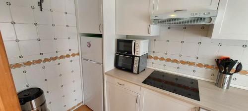 a small kitchen with a microwave and a refrigerator at Bungalow Iratxe en Santa Pola in Santa Pola