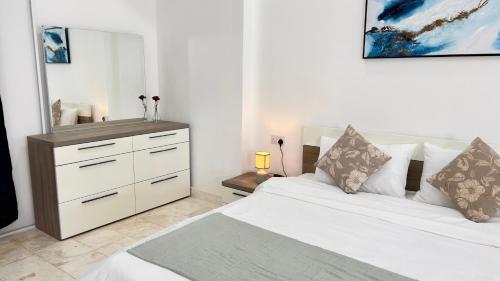 a bedroom with a white bed and a dresser at Wadi Shab Beach Villa in Sur