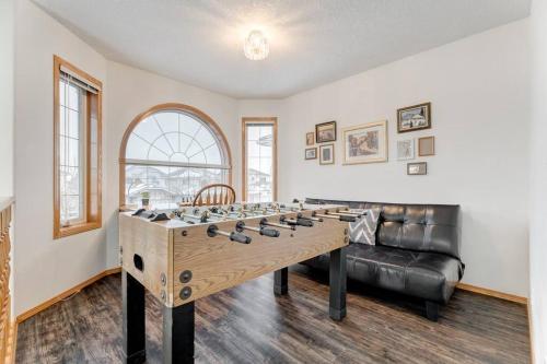 a large game room with a large wooden game table at Coral Springs Lakefront Retreat in Calgary