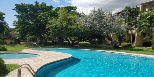 - une piscine dans une cour arborée dans l'établissement 1br, 24hr security - City Charm with Poolside Peace, à Port-d'Espagne