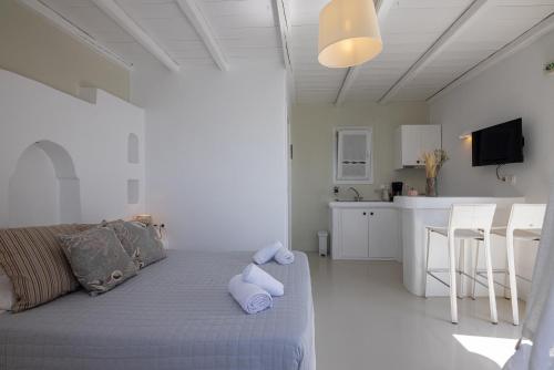 a white living room with a couch and a kitchen at Soulmate's Suites Tinos in Kionia