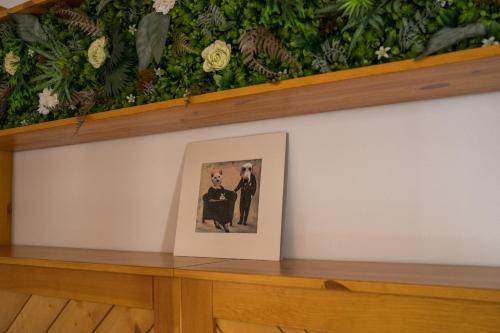 a picture of a couple on a shelf with flowers at Csipesz_Vendégház in Sümeg