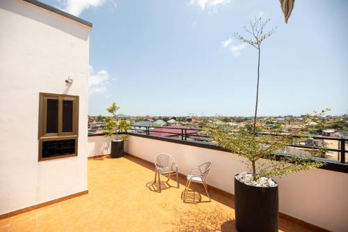 a balcony with two chairs and a potted tree at Impeccable 1-Bedroom Furnished Apartment in Accra in Accra
