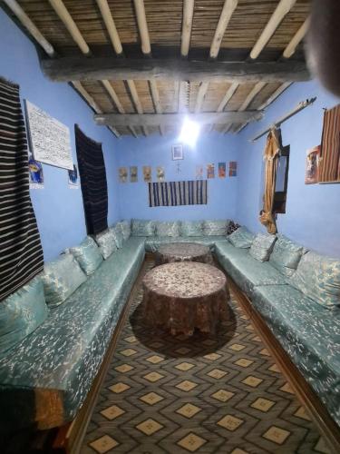 een kamer met een bank en een tafel met een boomstronk bij Gite d'étape chez zaid ouchaoua famille in Imilchil