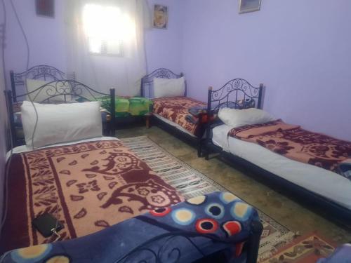 Cette chambre comprend 3 lits et un tapis. dans l'établissement Gite d'étape chez zaid ouchaoua famille, à Imilchil
