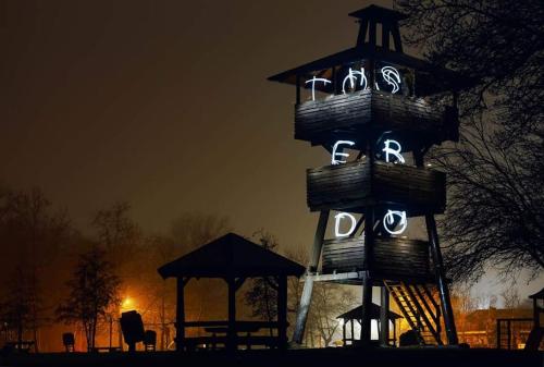 a clock tower that is lit up in the dark at Pintyőke Vendégház Tőserdő in Lakitelek