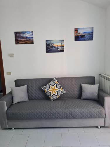 Szara kanapa z trzema zdjęciami na ścianie w obiekcie Casa Amelia lago Maggiore w mieście Maccagno Inferiore