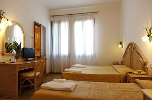 a hotel room with two beds and a desk and a mirror at Hotel Villa Orio & Beatrice in Venice-Lido