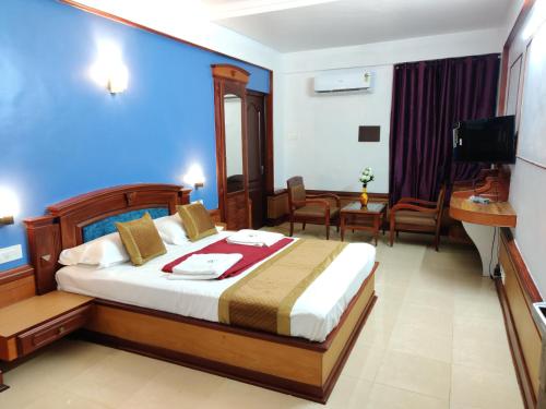 Habitación de hotel con cama y TV en Amruth Inn, en Guruvāyūr