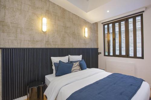 une chambre avec un grand lit avec des oreillers bleus dans l'établissement Apartment Saint Germain des Prés by Studio prestige, à Paris