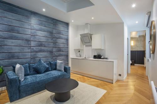 un salon avec un canapé bleu et une cuisine dans l'établissement Apartment Saint Germain des Prés by Studio prestige, à Paris