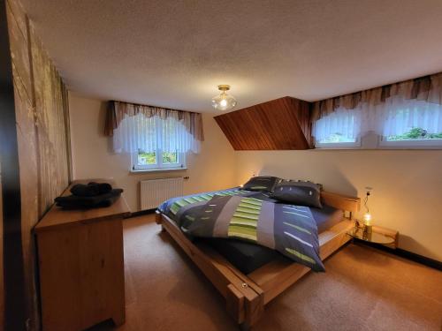 a bedroom with a large bed and two windows at Ferienhaus Sonnenblick Schmilka in Schmilka
