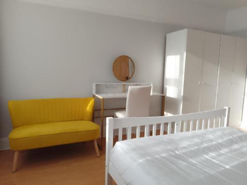 a bedroom with a bed and a yellow chair at Surbiton Home with free parkings, Surbiton, Kingston upon Thames, Surrey, Greater London UK in Surbiton