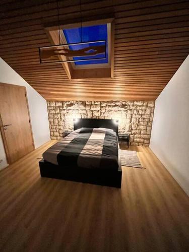 een slaapkamer met een bed en een stenen muur bij Le gîte du Mawet in Léglise