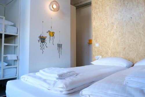 a bedroom with two beds with white sheets at Hostel & Bar De Basis in Zwolle