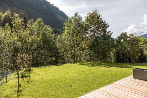 a garden with a wooden deck and green grass at Le Refuge Au Pied d'Hauto in Montriond