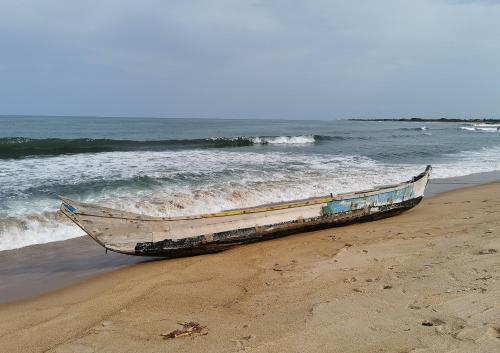 a boat sitting on the beach next to the ocean at A&Y Wild Camp Ghana in Keta