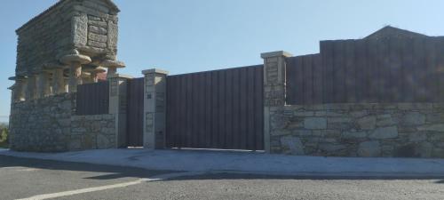 una valla con una puerta y una pared de piedra en A Casa Vella en Laxe