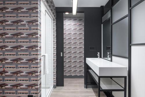 a bathroom with a white sink and a brick wall at Aloft Oklahoma City Quail Springs in Oklahoma City