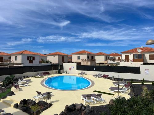 Una piscina con sillas y un resort. en Alcaudón HolidayFV, en Corralejo