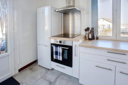 a white kitchen with a stove and a refrigerator at La Pause Douce Cosy à Angoulême - Confort, Lumière et Espace in Angoulême